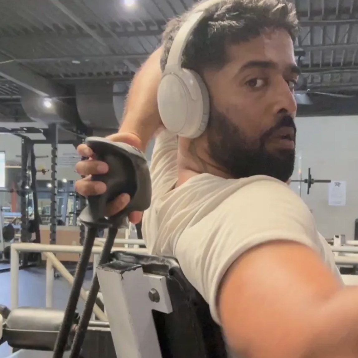 Vighnesh at the gym in headphones, mid-workout on a machine