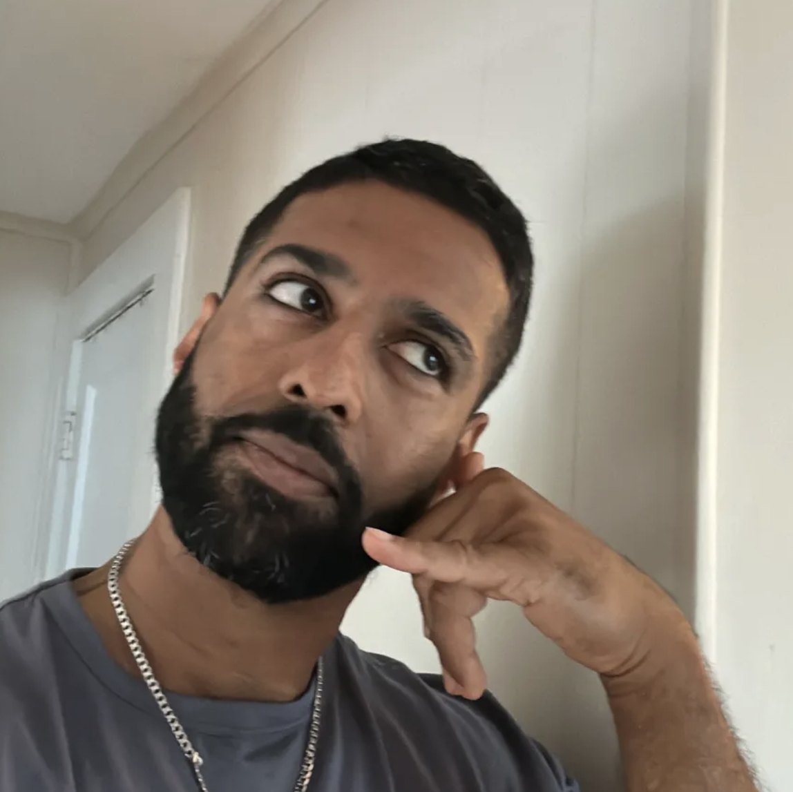 Vighnesh in a grey t-shirt, chin on his hand, glancing sideways
